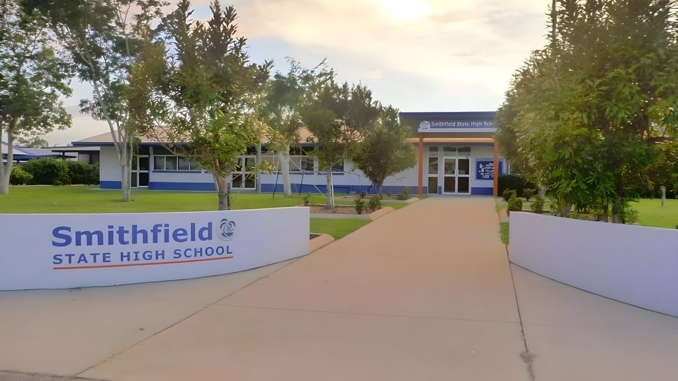 Das moderne Schulgebäude der Smithfield State High School ist zweistöckig und von Bäumen sowie einem gepflasterten Weg umgeben.