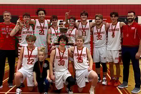 Schülerinnen und Schüler des Smiths Falls District Collegiate Institute posieren mit einem Basketball- Pokal in der Sporthalle.