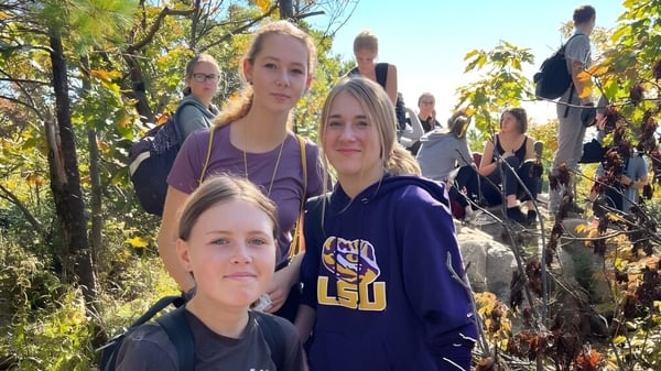 Eine Gruppe Schülerinnen der Smiths Falls District Collegiate Institute steht in einem herbstlichen Waldgebiet.