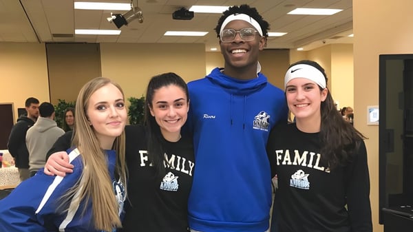 Eine Gruppe von vier Personen steht gemeinsam in einem Raum der Smithtown Christian School und lächelt.