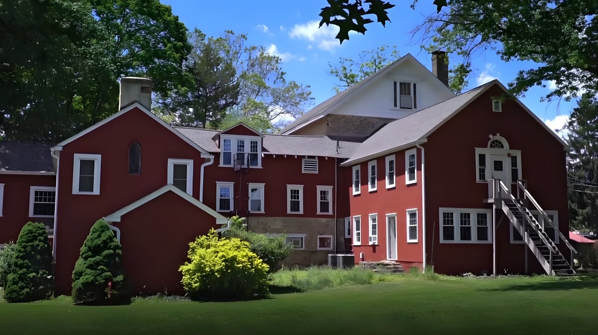 Das rote Backsteingebäude ist von grüner Landschaft umgeben und befindet sich auf dem Gelände der Solebury School.