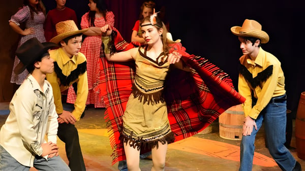 Schüler der Solebury School führen einen traditionellen Kulturtanz auf einer Bühne mit dunklem Hintergrund auf.