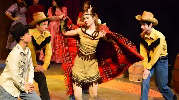 Schüler der Solebury School führen einen traditionellen Kulturtanz auf einer Bühne mit dunklem Hintergrund auf.