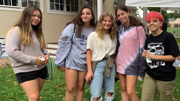 Eine Gruppe von fünf Schülerinnen steht zusammen vor einem Gebäude auf dem Campus der Solebury School.