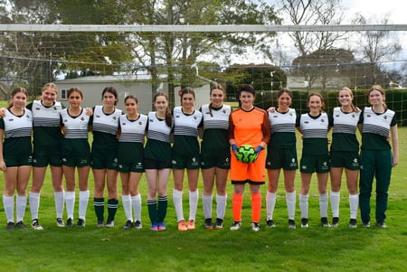 Eine Gruppe junger Fußballspielerinnen steht gemeinsam auf dem Sportplatz des Solway College.