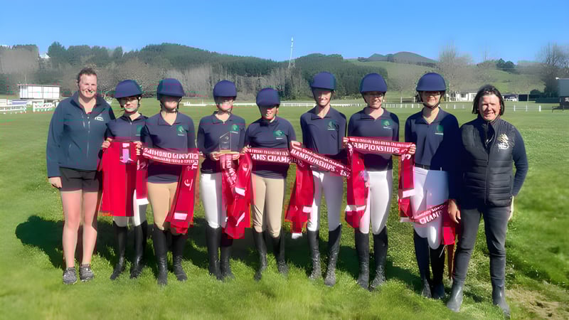 Eine Gruppe von Schülerinnen und Schülern des Solway College steht auf einem Feld mit Bergen und Bäumen im Hintergrund.