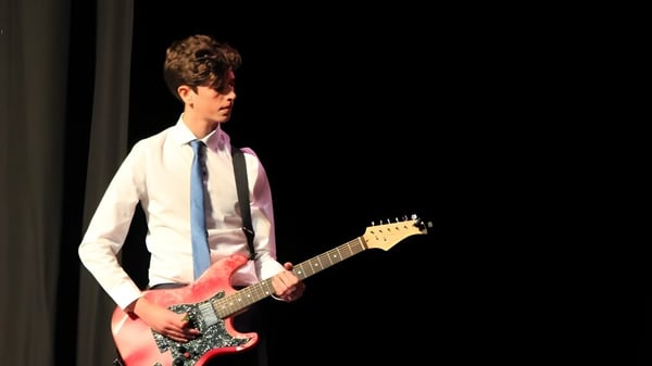 Eine Person spielt auf einer dunklen Bühne eine E-Gitarre im Somerset Studio School.