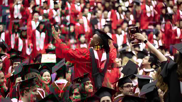 Eine große Gruppe von Absolventen in roten Talaren feiert auf der Abschlussfeier der Somervale School in einer Innenhalle.