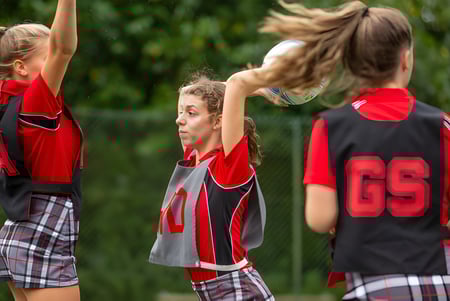 Drei junge Sportlerinnen der Somervale School wärmen sich draußen auf einer Wiese auf.