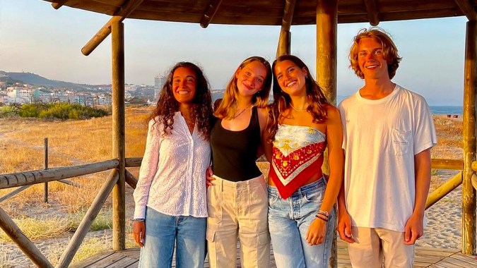 Vier Schüler der Sotogrande International School stehen lächelnd in einem Holzpavillon mit Blick auf eine bergige Landschaft.
