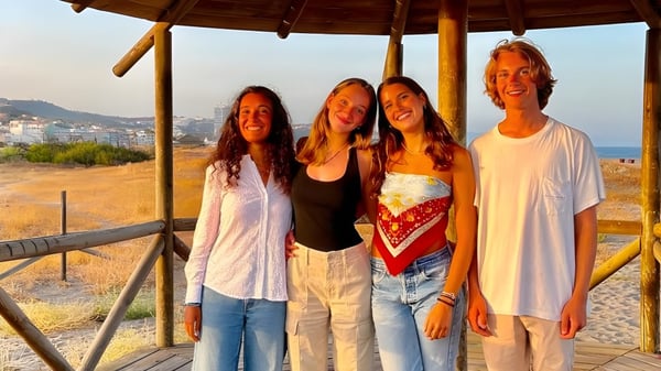 Eine Gruppe von vier Schülerinnen und Schülern steht in einem Holzpavillon mit Blick auf die Küstenlandschaft auf dem Campus der Sotogrande International School.