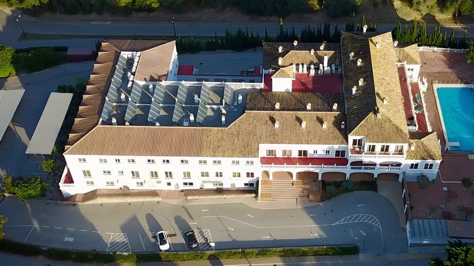 Luftaufnahme eines großen schlossähnlichen Gebäudes auf dem Campus der Sotogrande International School mit umgebendem Grün und Wasser.