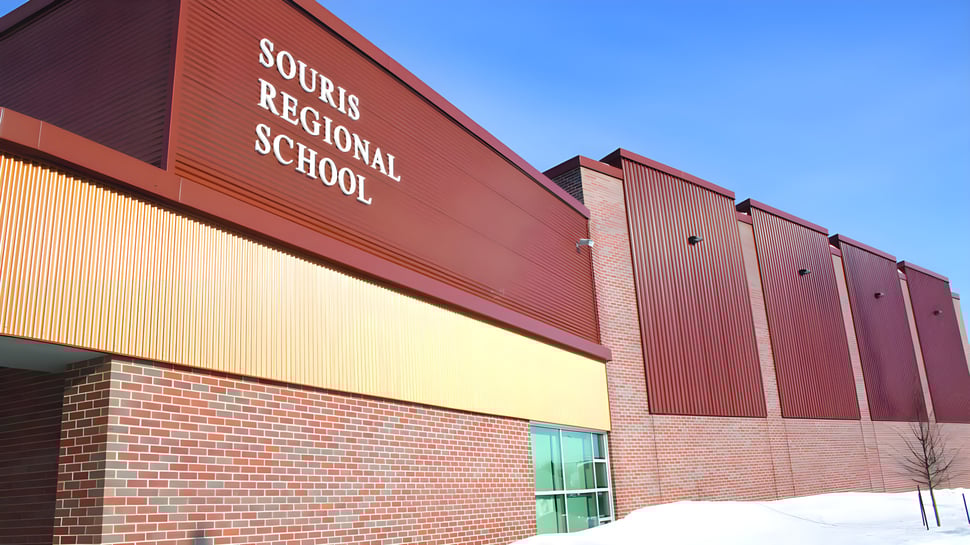 Das große rote Backsteingebäude der Souris Regional School ist bei klarem Himmel mit Schnee im Vordergrund zu sehen.