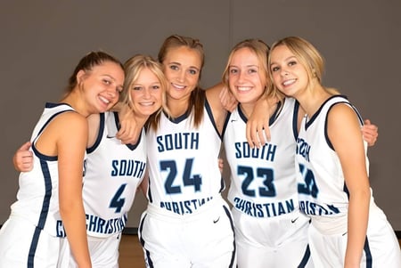 Fünf Schülerinnen der South Christian High School posieren in Basketball-Trikots in einer Sporthalle.
