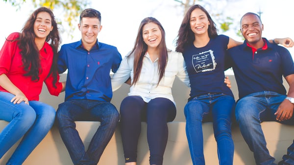 Eine Gruppe von fünf Schülerinnen und Schülern sitzt lachend im Freien auf dem Gelände des South Hill Education Centre.