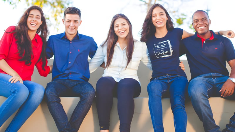 Eine Gruppe von fünf Schülerinnen und Schülern sitzt lachend im Freien auf dem Gelände des South Hill Education Centre.