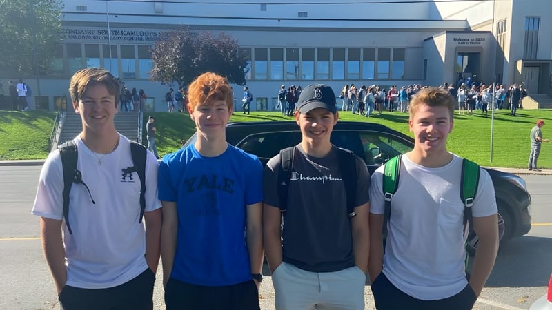 Vier Schüler stehen gemeinsam vor einem großen Gebäude auf dem Campus der South Kamloops Secondary School.