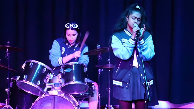 Zwei Schülerinnen und Schüler vom Southern River College treten gemeinsam auf der Bühne mit Schlagzeug und Gesang auf.
