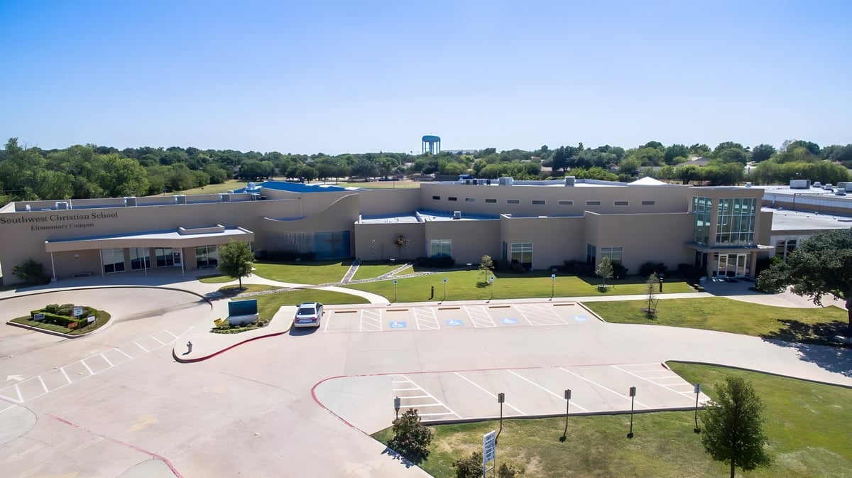 Das moderne Hauptgebäude der Southwest Christian Academy mit Wasserturm und umgebender Grünfläche mit Wegen.