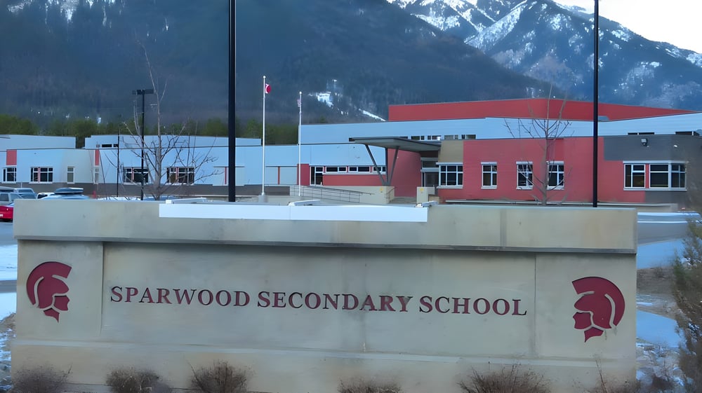 Das moderne Schulgebäude der Sparwood Secondary School mit roter und weißer Fassade vor schneebedeckten Bergen.