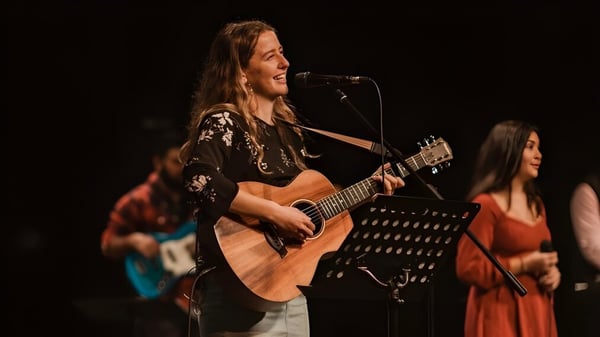 Eine Schülerin der Spectrum Community Secondary School spielt akustische Gitarre auf einer Bühne mit anderen Musikern.