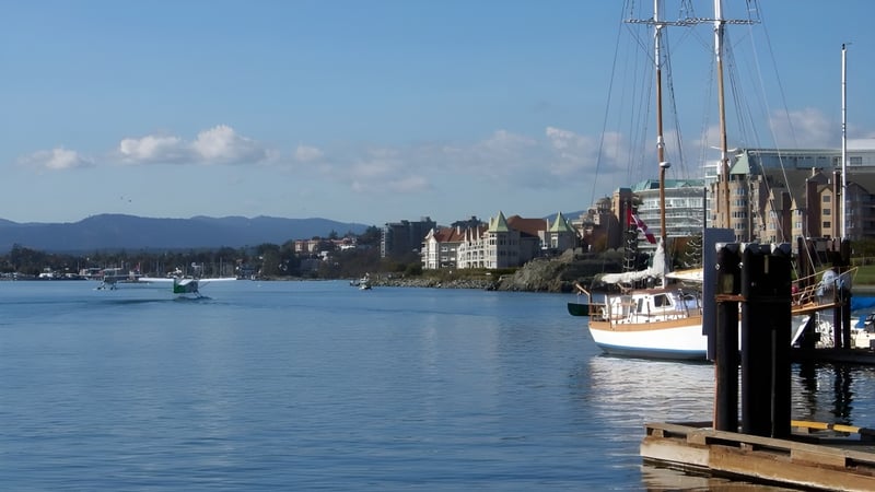 Blick auf den Hafen und die Segelboote in der Nähe der Spectrum Community Secondary School vor einer Bergkulisse.