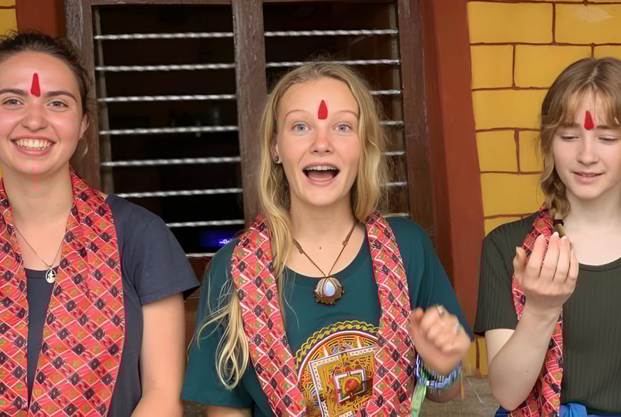 Drei Schuelerinnen der Spring Street International School zeigen vor einer gelben Backsteinwand expressive Gesichtsausdruecke.