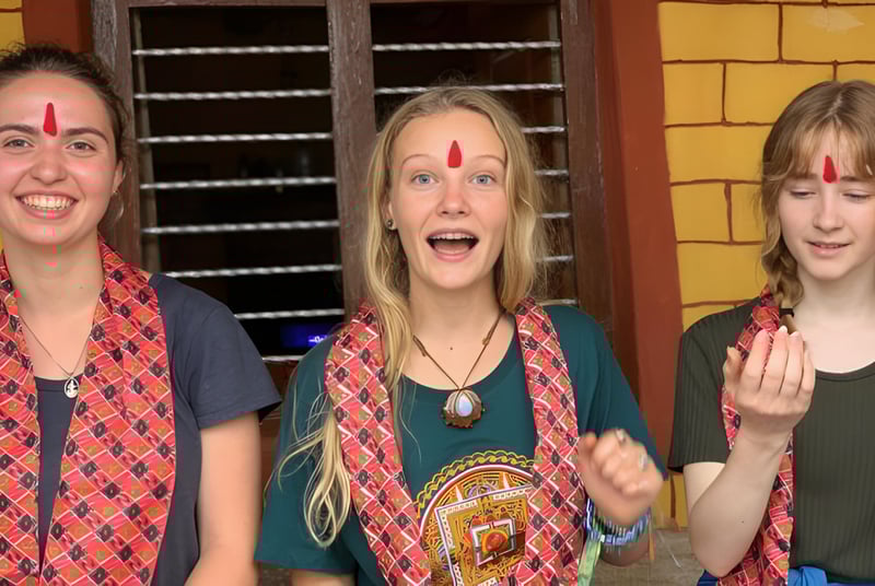 Drei Schuelerinnen der Spring Street International School zeigen vor einer gelben Backsteinwand expressive Gesichtsausdruecke.