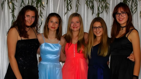 Fünf junge Frauen in formeller Kleidung posieren gemeinsam vor einem Vorhang auf dem Campus der Springbank School.