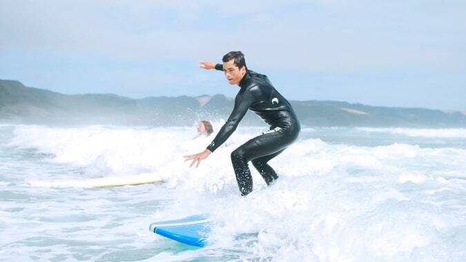 Eine Person surft auf einer Welle im Ozean vor Bergen auf dem Gelände der Springbank School.