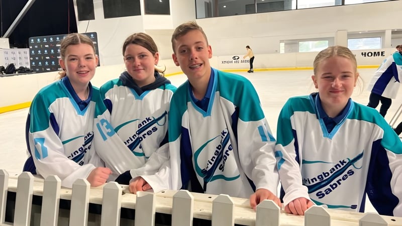 Eine Gruppe von Schülerinnen und Schülern des Springbank Secondary College steht gemeinsam in Sporttrikots auf einer Eisfläche.
