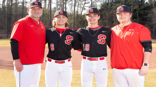 Vier Schüler der Springwood School tragen Baseballuniformen und stehen im Wald zusammen.