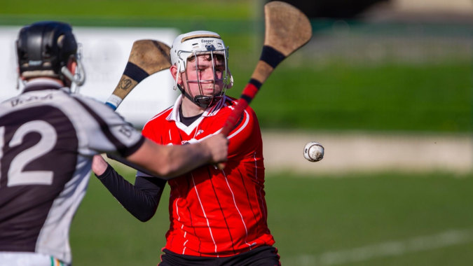 Zwei Schüler der St. Aidan's Comprehensive School spielen Fußball auf einem Grasfeld, einer trägt ein rotes Trikot, der andere ein schwarzes.