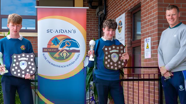 Drei Schüler der St. Aidan's Comprehensive School stehen vor einem Backsteingebäude mit einem großen Schild der Schule.