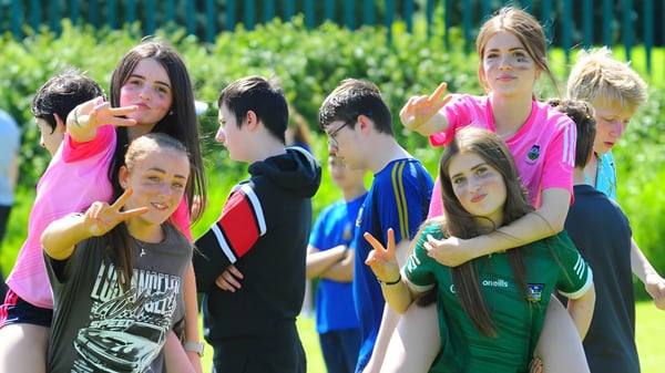 Eine Gruppe Schülerinnen und Schüler steht auf einer Wiese vor Bäumen auf dem Gelände der St Ailbe's School.