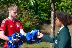 Zwei Schüler der St. Alban's Catholic High School unterhalten sich im Freien vor grüner Vegetation.