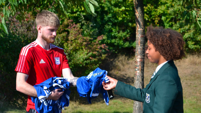 Zwei Schüler der St. Alban's Catholic High School stehen in einem Waldgebiet und diskutieren miteinander.