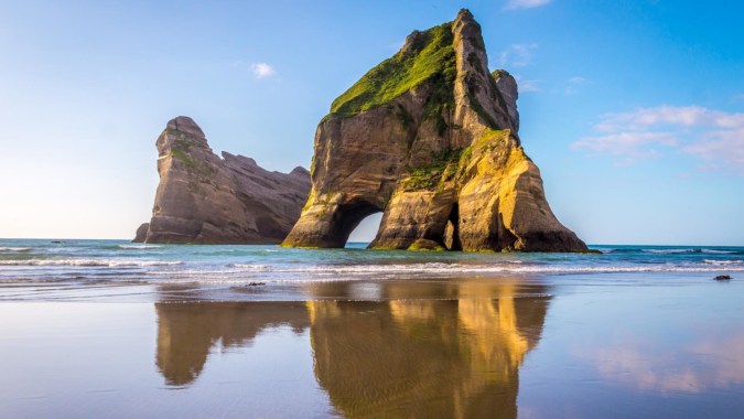 Felsen mit grünen und gelben Farbtönen spiegeln sich im ruhigen Wasser auf dem Gelände von St. Andrew's College.