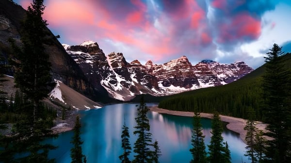 Ein idyllischer See zwischen schneebedeckten Bergen spiegelnd den farbenfrohen Himmel auf dem Gelände von St. Andrew’s College.