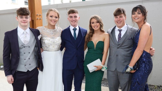 Eine Gruppe gut gekleideter Personen posiert vor dem modernen Gebäude des St. Andrew's College bei einer Veranstaltung.