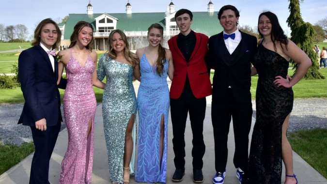 Eine Gruppe elegant gekleideter Personen steht vor dem historischen Gebäude auf dem Campus von St. Andrew's College.