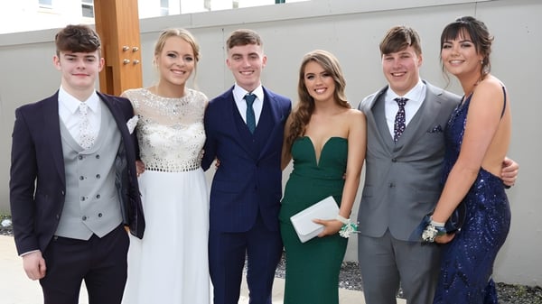 Eine Gruppe von Personen steht vor dem modernen Gebäude des St. Andrew's College bei einer formellen Veranstaltung.