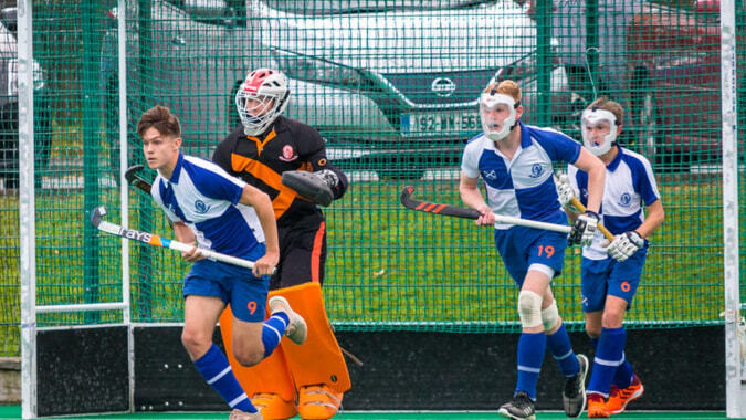 Schüler des St. Andrew's College spielen Hockey auf dem umzäunten Spielfeld mit grünem Kunstrasen.