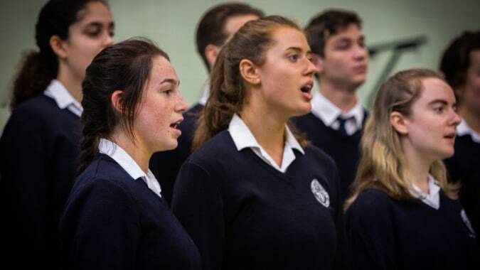 Eine Gruppe Schüler des St. Andrew's College steht gemeinsam in einem Klassenraum und singt.