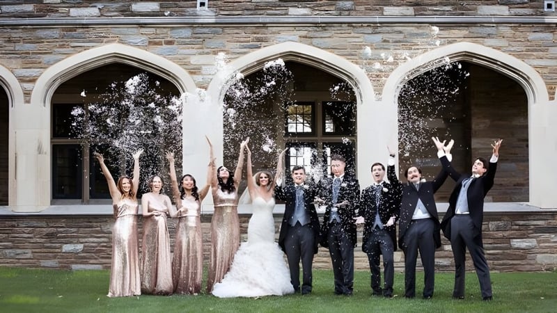 Schüler der St. Andrew's School feiern vor einem historischen Gebäude mit Bogenfenstern und werfen Konfetti in die Luft.