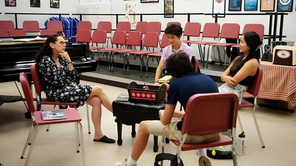 Eine Gruppe Schüler sitzt im Klassenzimmer der St. Andrew's School mit Stühlen und Klavier im Hintergrund.