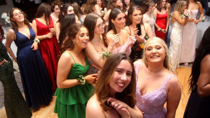 Eine Gruppe Schülerinnen in Abendkleidern posiert gemeinsam auf dem Campus von St. Angela’s College.