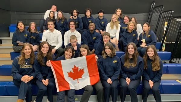 Eine Gruppe Schülerinnen in Uniformen der St. Anne Catholic High School hält gemeinsam eine kanadische Flagge.