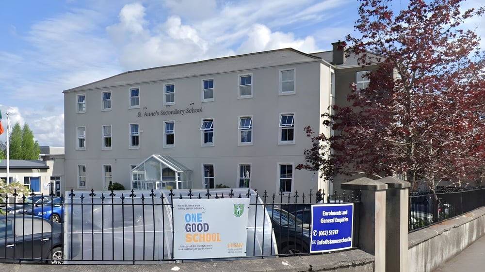 Das mehrstöckige Gebäude der St. Anne's Secondary School ist von einem Metallzaun umgeben und von Bäumen mit roten Blättern umrahmt.