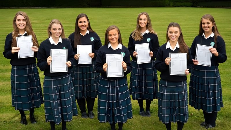 Sechs Schülerinnen der St. Anne's Secondary School stehen im Freien und halten ihre Zertifikate in einer grünen Umgebung hoch.